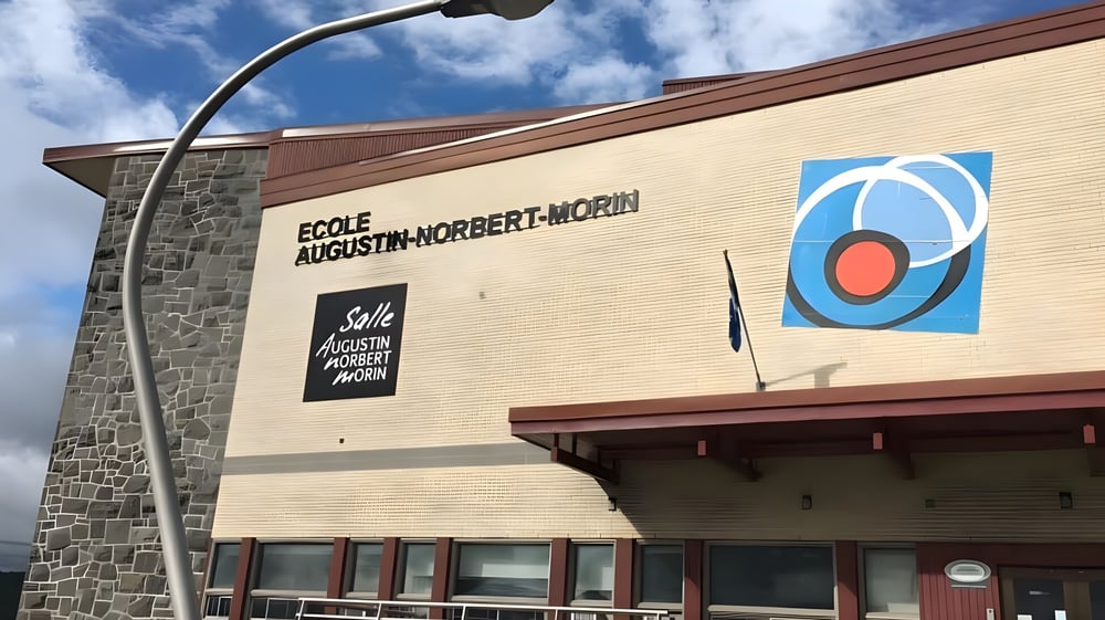 Das Schulgebäude der École Secondaire Augustin-Norbert-Morin zeigt eine Fassade aus Stein und Backstein mit einem großen Schulnamen-Schild.