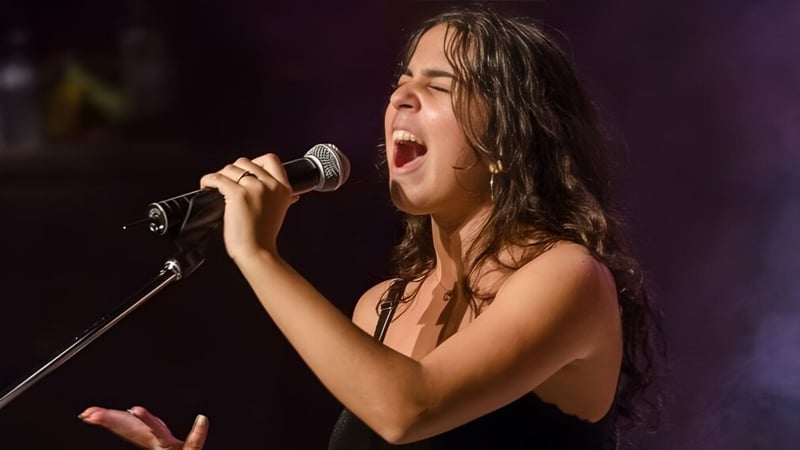 Eine Schülerin der École Secondaire Augustin-Norbert-Morin singt leidenschaftlich in ein Mikrofon auf einer Bühne.