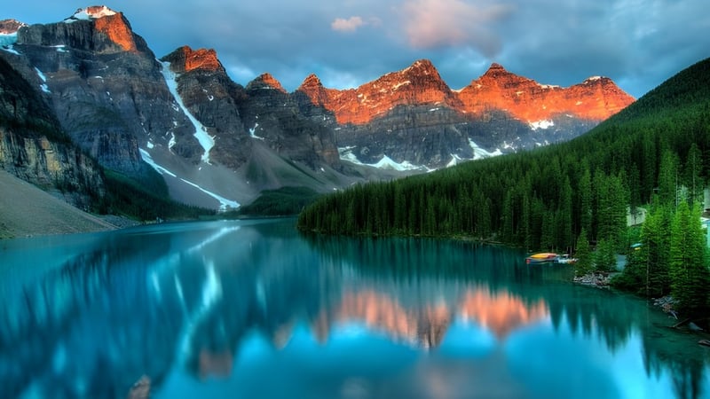 Ein ruhiger alpiner See mit schneebedeckten Bergen spiegelt sich im Wasser auf dem Campus der École Aux quatre vents.