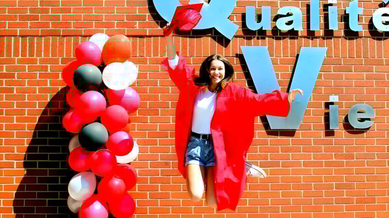 Eine Frau in rotem Outfit steht vor einer bunten Ballonwand an der École Aux quatre vents.