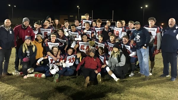 Eine große Gruppe von Schülerinnen und Schülern der École Camrose Composite High School versammelt sich nachts auf einem Feld mit Trikot und Schildern.