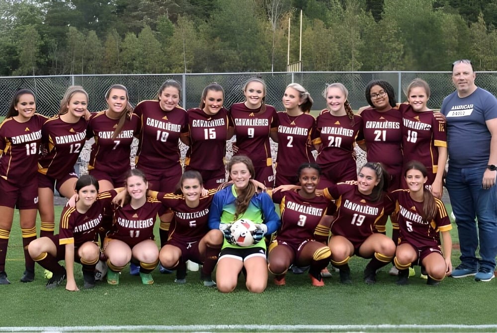 Eine Gruppe junger Fußballspielerinnen posiert auf dem Sportplatz der École Clément-Cormier.