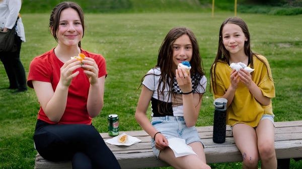 Drei Schülerinnen der École Côte du Soleil sitzen auf einer Holzbank im Freien und essen Eis.