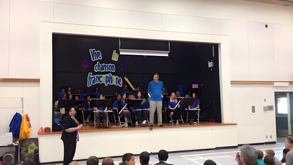 Eine Gruppe von Musikern und ein Dirigent führen auf der Bühne der École des Deux-Rives ein Konzert auf.