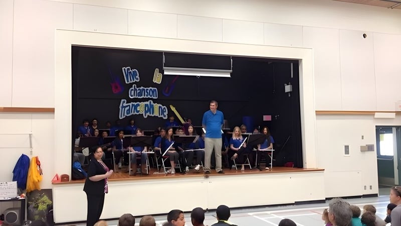 Eine Gruppe von Musikern und ein Dirigent führen auf der Bühne der École des Deux-Rives ein Konzert auf.