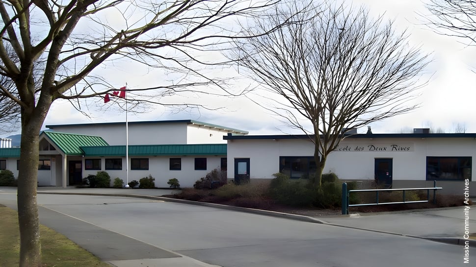 Ein kahler Baum steht vor einem Geschäftsgebäude und Parkplatz auf dem Gelände der École des Deux-Rives.