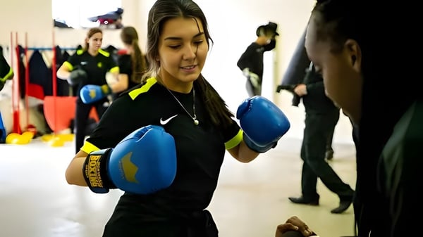 Eine junge Frau mit Boxhandschuhen trainiert in der Sporthalle der Ecole des roches.