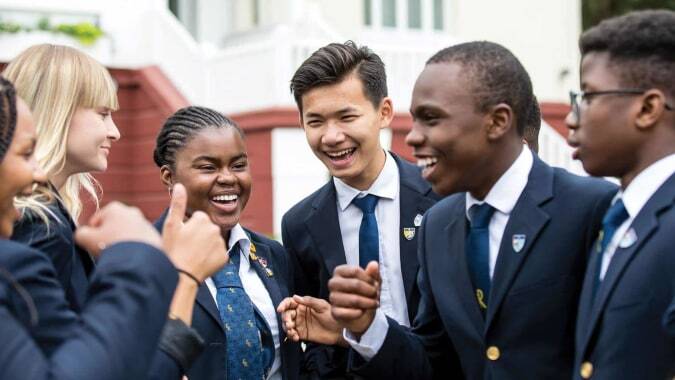 Eine Gruppe diverser Schülerinnen und Schüler der Ecole des roches unterhält sich lebhaft in Schuluniform.