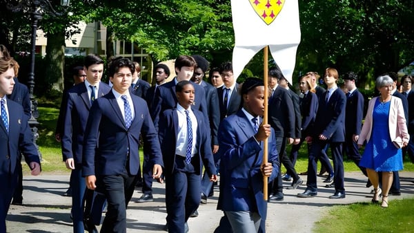 Eine Gruppe Schüler der Ecole des Roches geht gemeinsam auf einem von Bäumen gesäumten Weg.