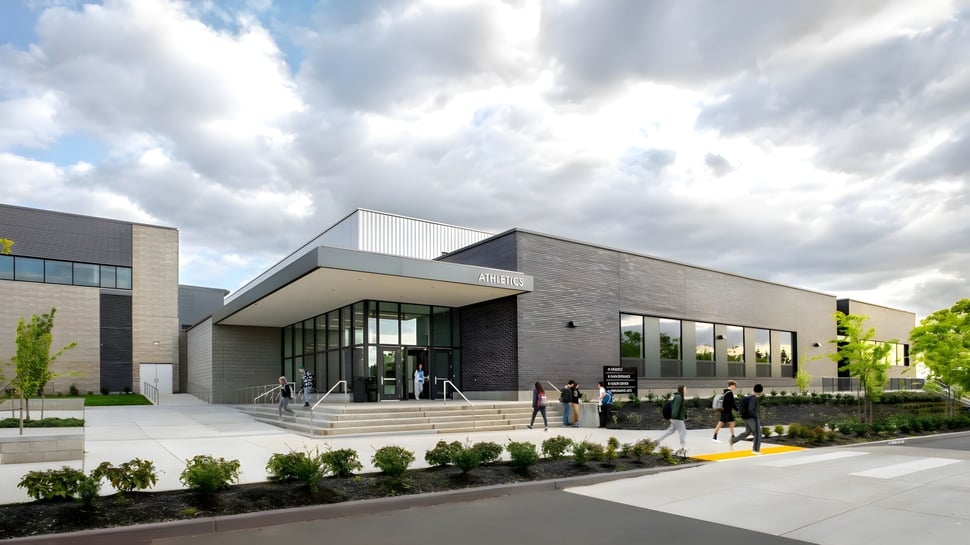 Das moderne Gebäude der École des Sentiers-Alpins mit Glas-Eingang und gestalteter Umgebung unter bewölktem Himmel.