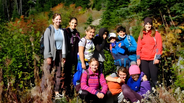Schülerinnen und Schüler der École des Sentiers-Alpins stehen in einem Wald mit buntem Herbstlaub.