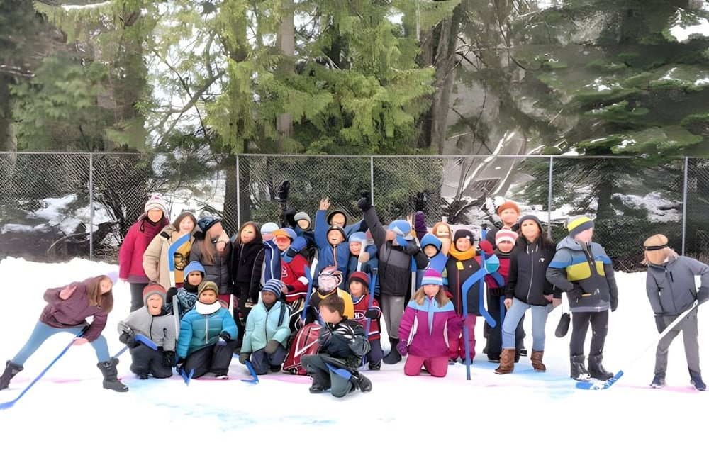 Eine Gruppe von Schülern der École des Sentiers-Alpins steht im verschneiten Außenbereich unter Bäumen.