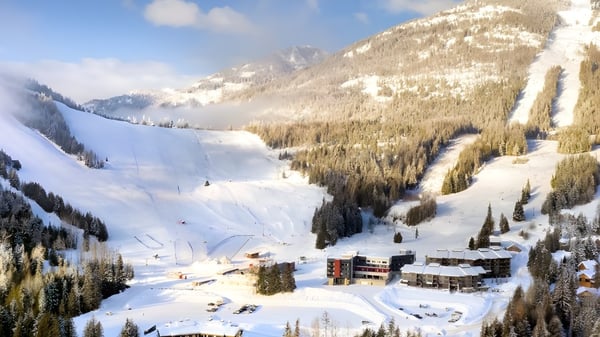 Das verschneite Bergpanorama mit einem Skigebiet liegt in einem Tal nahe der École des Sept Sommets.