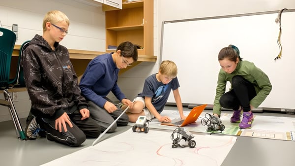 Eine Gruppe von Schülern der École des Sept Sommets untersucht gemeinsam kleine Objekte in einer Werkstatt.