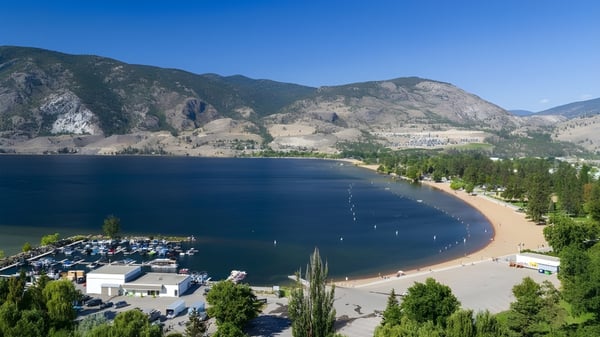 Blick auf einen See mit Sandstrand und Bootshafen in der Landschaft nahe der École Entre-Lacs.