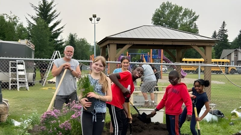 Eine Gruppe von Schülern und Erwachsenen befindet sich im Außenbereich der École Franco-Nord mit Bäumen und einem Pavillon im Hintergrund.