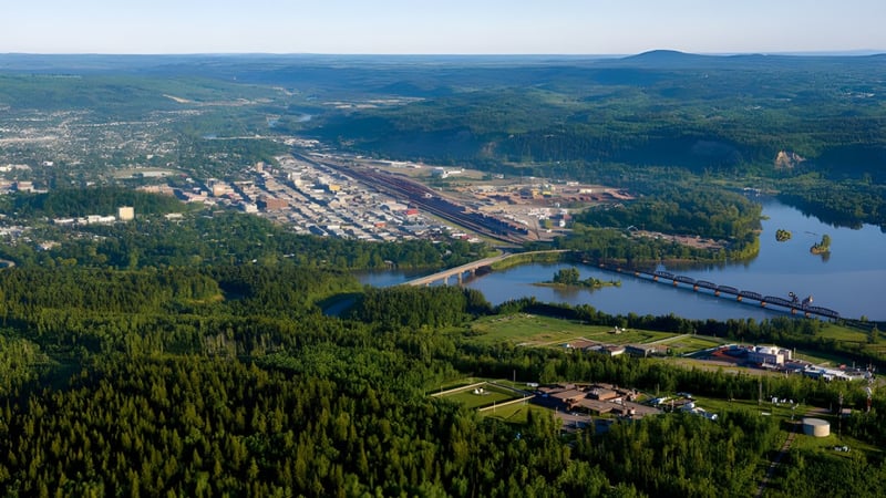 Blick auf eine bewaldete Landschaft mit Fluss und einem kleinen Ort im Tal nahe der École Franco-Nord.