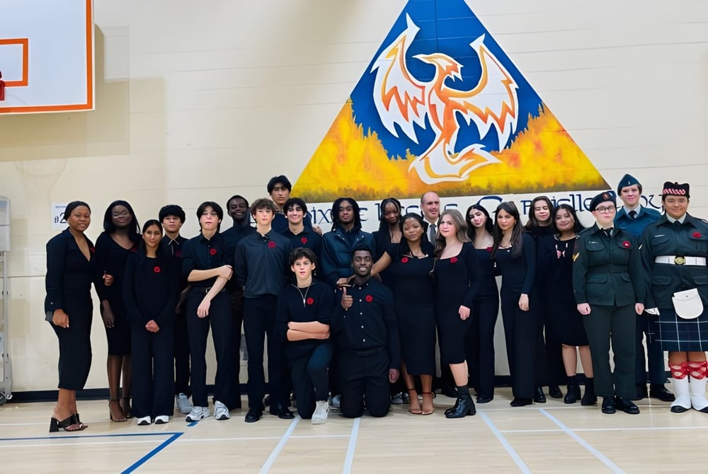 Eine Gruppe Schülerinnen und Schüler steht vor einem großen Wandbild mit einem phönixartigen Wesen an der École Gabrielle-Roy.