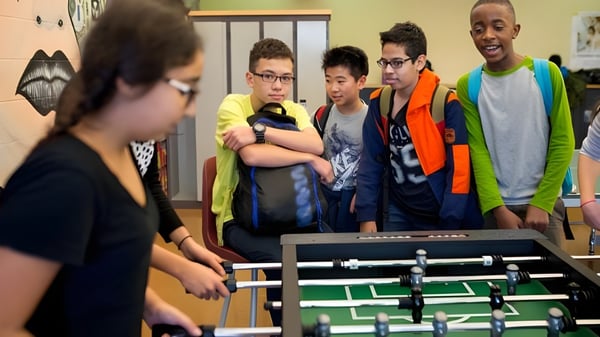 Schüler der École Gabrielle-Roy spielen gemeinsam an einem Tischfußballtisch im Schulgebäude.