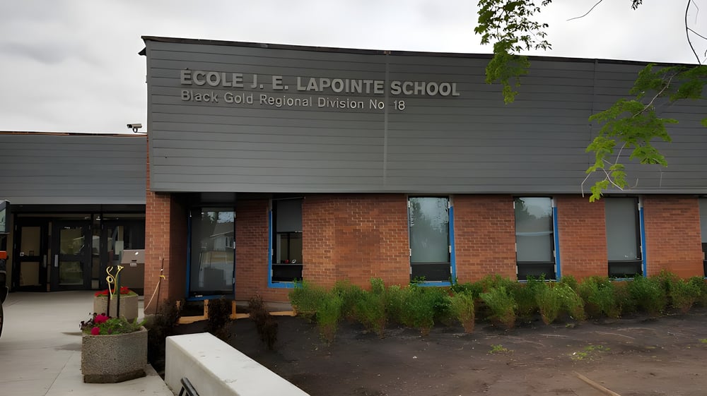 Das Gebäude der École J.E. Lapointe School mit Backsteinfassade und begrünten Außenanlagen ist zu sehen.
