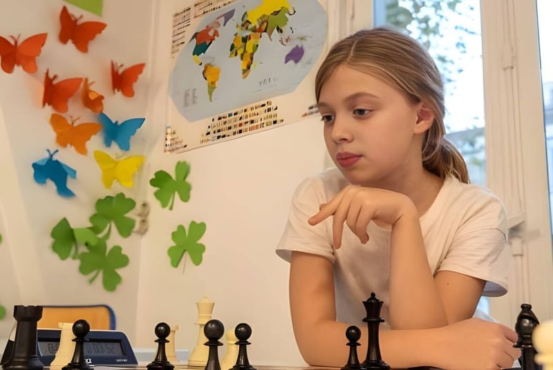 Ein Mädchen sitzt an einem Tisch mit Schachfiguren und einer Weltkarte auf dem Campus der École Jeannine Manuel.