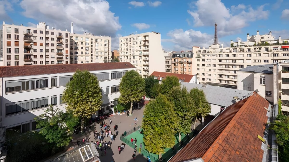 Blick auf einen grünen Park mit modernen und historischen Gebäuden im Hintergrund in der Nähe der École Jeannine Manuel.