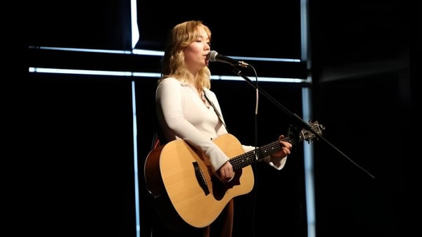 Eine Schülerin der École L’Odyssée spielt Gitarre und singt bei einem Auftritt auf der Bühne.
