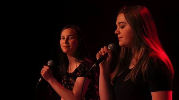 Zwei Schülerinnen der École Polyvalente des Monts treten auf der Bühne unter roter Beleuchtung auf.