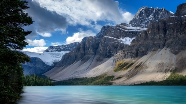 Ein türkisfarbener See liegt zwischen schneebedeckten Bergen vor der École Polyvalente des Monts.