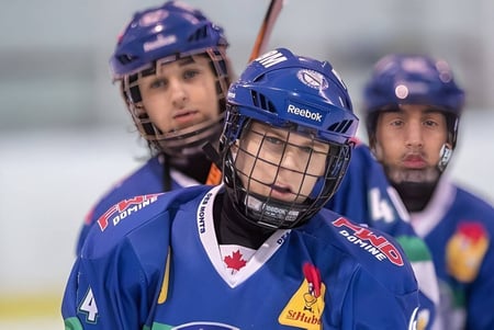 Drei Hockeyspieler in blauen Uniformen stehen auf dem Eis in der Halle der École Polyvalente des Monts.