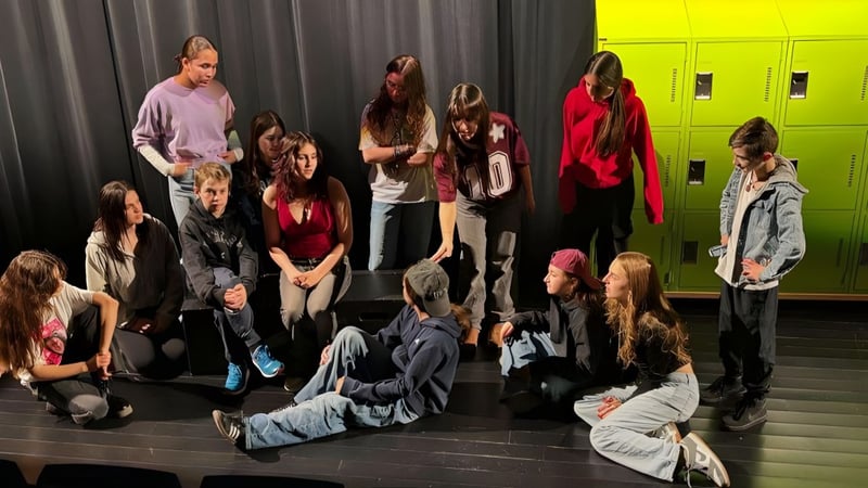 Eine Gruppe von Schülerinnen und Schülern der École secondaire publique Rivière Rideau steht auf einer Bühne vor bunten Schließfächern.