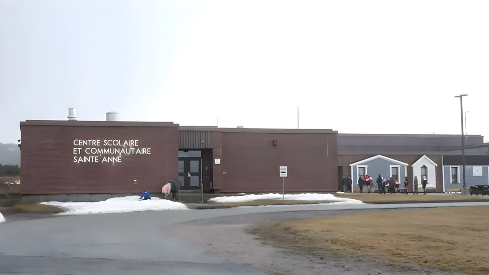 Das Gebäude der École Sainte-Anne aus braunen Ziegeln mit Schnee auf dem umliegenden Gras.