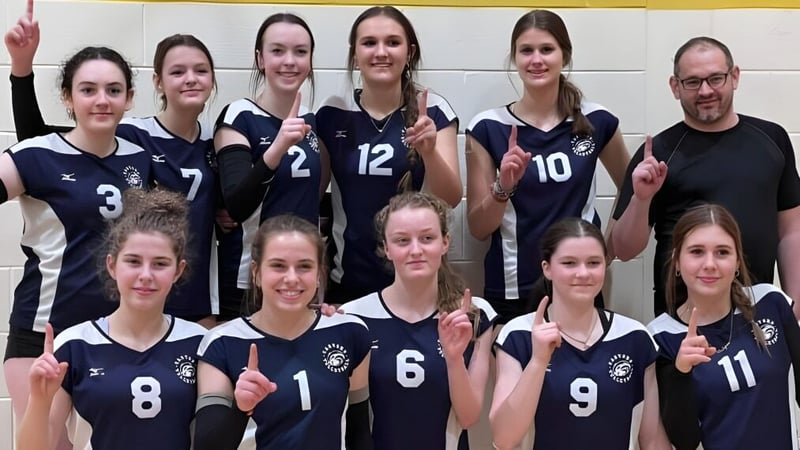 Eine Gruppe weiblicher Volleyballspielerinnen steht zusammen im Sportbereich der École Sainte-Anne.