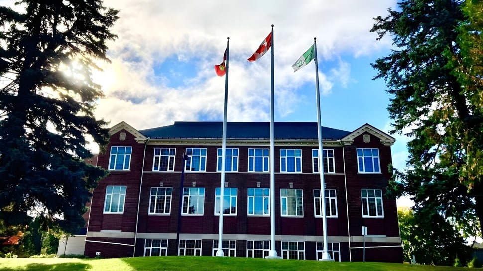 Das mehrstöckige Backsteingebäude der École secondaire publique L'Alternative umgeben von Bäumen in einer parkähnlichen Umgebung.