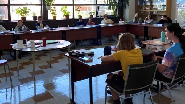 Eine Gruppe Schüler sitzt in einem hellen Klassenraum der École secondaire publique L'Alternative mit Blick ins Freie.