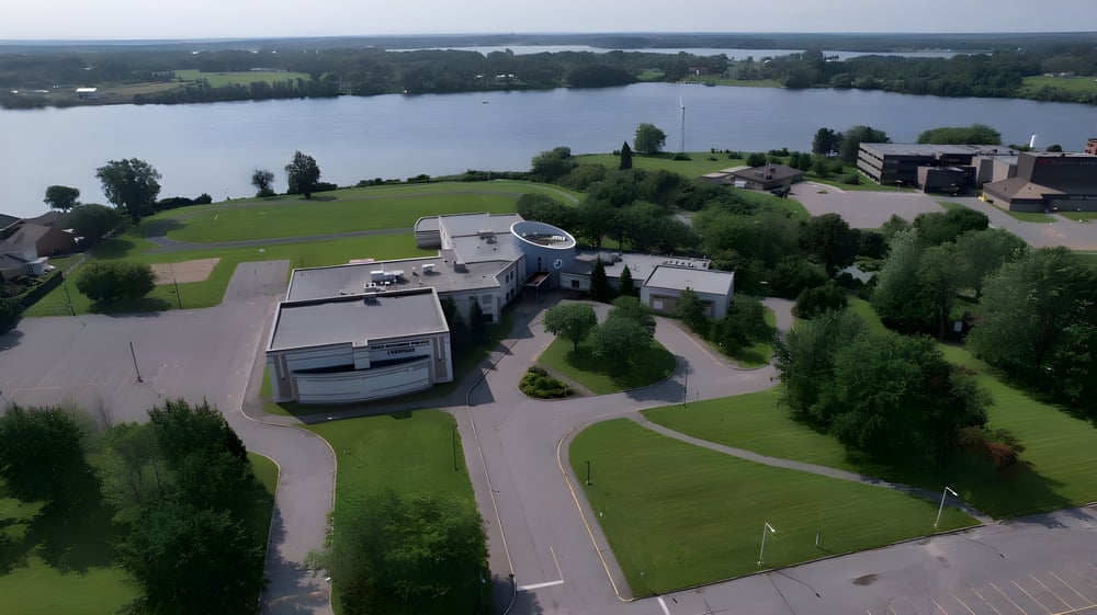 Luftaufnahme des Seeferienorts mit grünen Rasenflächen und Gebäuden auf dem Gelände der École secondaire publique L'Héritage.