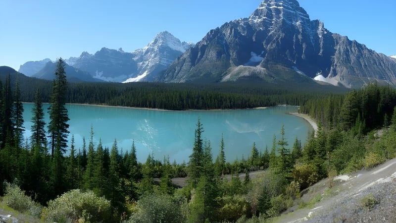 Ein ruhiger türkisfarbener See liegt inmitten schneebedeckter Berge und einem immergrünen Wald auf dem Gelände der École secondaire Népisiguit.