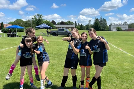 Eine Gruppe junger Athletinnen steht auf einem Sportfeld auf dem Gelände der École secondaire publique Rivière Rideau.