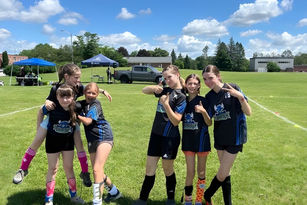 Eine Gruppe junger Athletinnen steht auf einem Sportfeld auf dem Gelände der École secondaire publique Rivière Rideau.