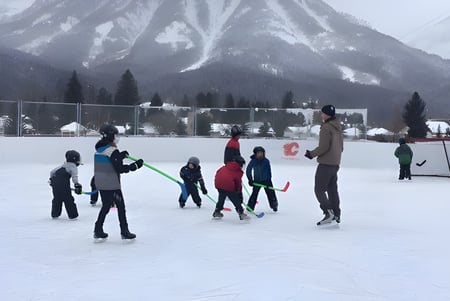Schüler der École Sophie Morigeau beim Eislaufen auf einer zugefrorenen Bahn vor verschneiter Berglandschaft.