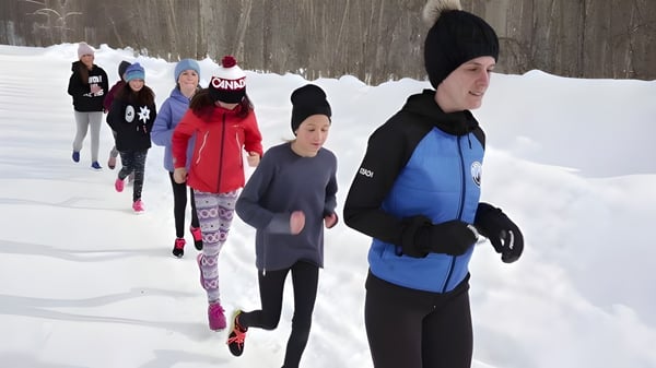 Schüler der École Sophie Morigeau gehen in warmer Winterkleidung durch einen verschneiten Wald mit kahlen Bäumen.