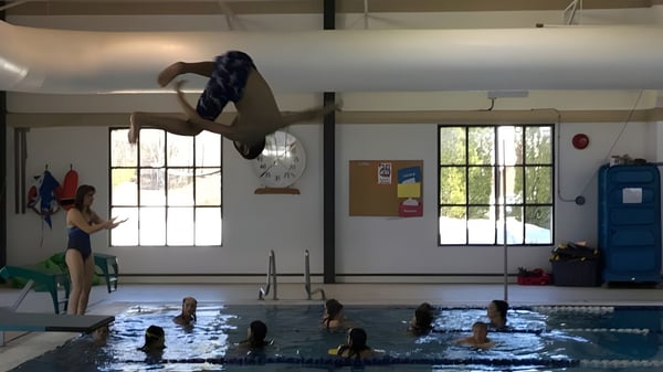 Eine Person führt einen Sprung ins Hallenbad auf dem Campus der École Sophie Morigeau aus.