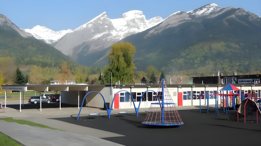Ein bunter Spielplatz auf dem Gelände der École Sophie Morigeau vor schneebedeckten Bergen im Hintergrund.