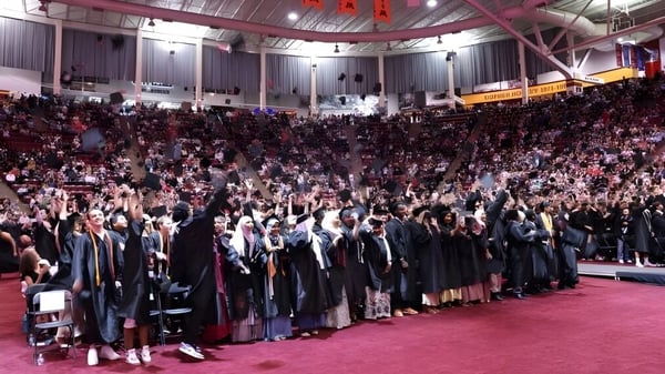 Schüler der Eden Prairie Schools versammeln sich in ihren Abschlussgewändern bei einer Zeremonie in einer großen Halle.