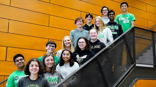 Eine Gruppe Schüler steht auf einer Treppe vor einer orangefarbenen Wand auf dem Campus der Edina Public Schools.