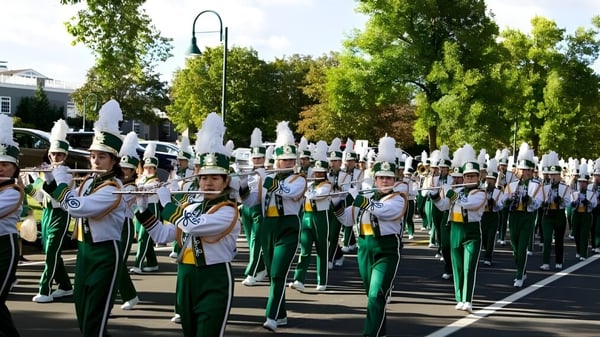Die Marching Band der Edina Public Schools tritt in grünen und weißen Uniformen auf einer von Bäumen gesäumten Straße auf.