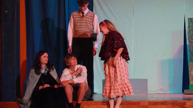 Schüler der Edinburgh Steiner School stehen und sitzen in verschiedenen Posen auf einer Bühne während einer Aufführung.