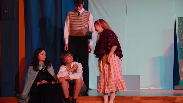 Schüler der Edinburgh Steiner School führen auf einer Bühne in farbenfrohen Kostümen ein Theaterstück auf.