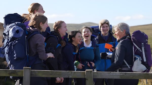 Eine Gruppe von Schülern der Edinburgh Steiner School steht auf einer hölzernen Plattform im Freien mit Blick auf hügelige Landschaft und klaren Himmel.