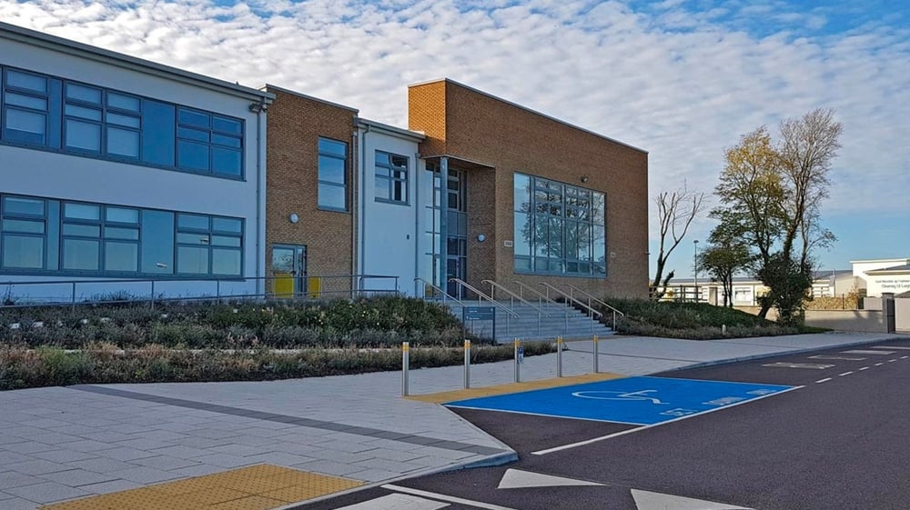 Das moderne mehrstöckige Backsteingebäude mit großen Fenstern und einem gepflasterten Außenbereich befindet sich auf dem Campus des Edmund Rice College.